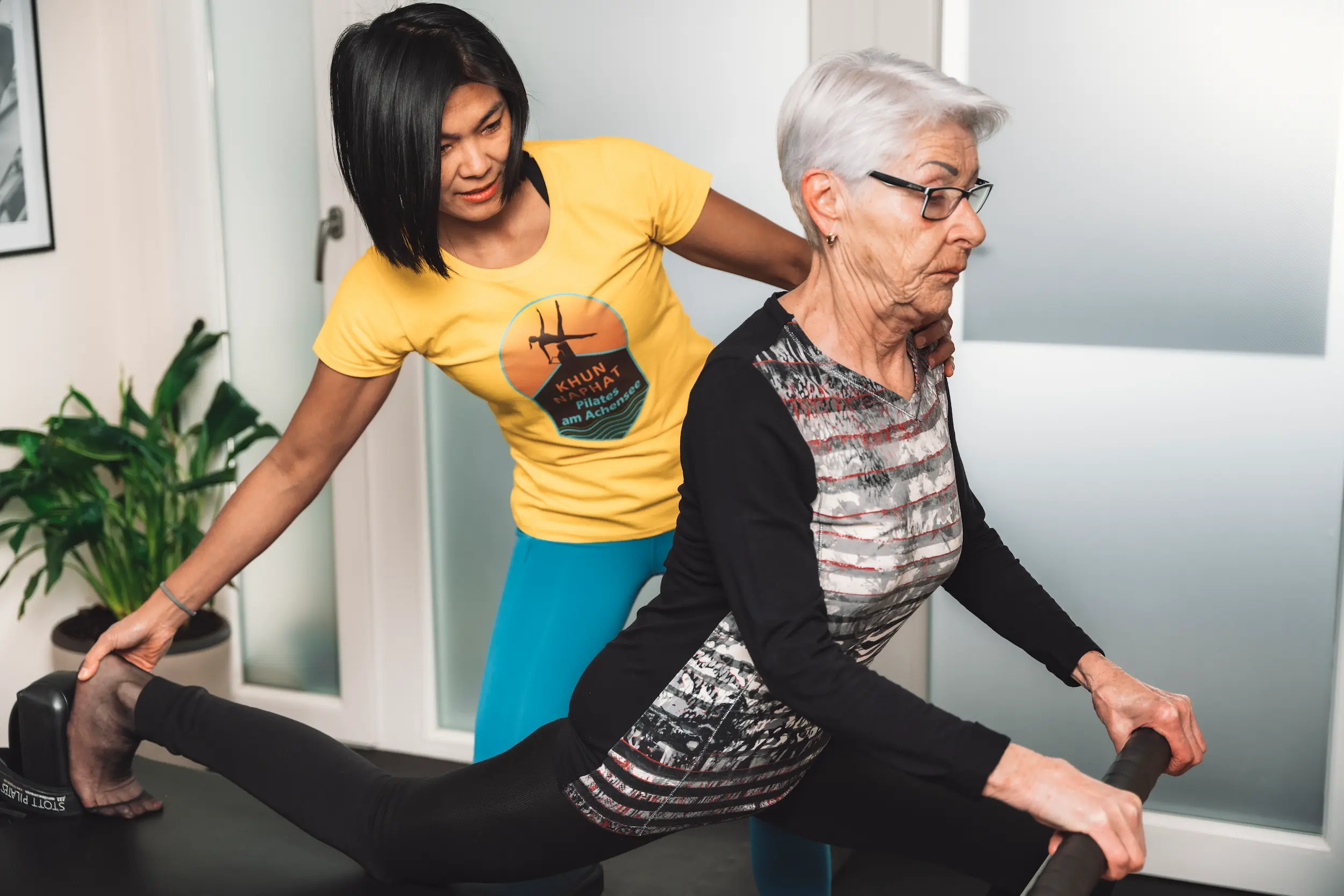 Pilates-Trainerin korrigiert Haltung einer Seniorin bei Stretching-Übung am Reformer in Maurach am Achensee